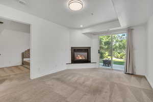 Unfurnished living room featuring carpet flooring and a glass covered fireplace