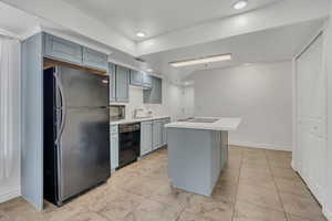Kitchen with black appliances, light countertops, gray cabinets, light tile patterned flooring, and recessed lighting