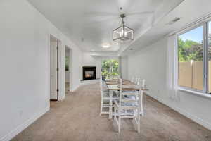 Dining space featuring light colored carpet, a glass covered fireplace, and a chandelier