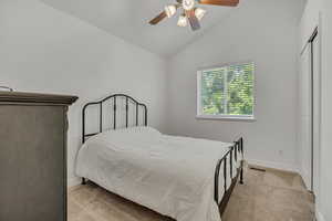 Carpeted bedroom featuring lofted ceiling and ceiling fan