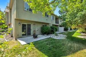 Back of house with stucco siding, a patio area, a lawn, and an outdoor fire pit