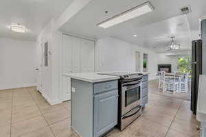 Kitchen featuring stainless steel electric range, light tile patterned flooring, a center island, and open floor plan