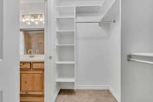 Spacious closet with carpet floors and a chandelier