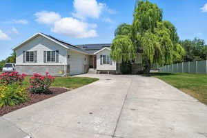 Single story home featuring concrete driveway, solar panels, and a garage