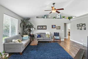 Living room with ceiling fan, wood finished floors, and high vaulted ceiling