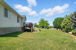 View of green lawn featuring a wooden deck
