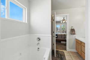 Full bath with a garden tub, vanity, ensuite bathroom, tile patterned floors, and a ceiling fan
