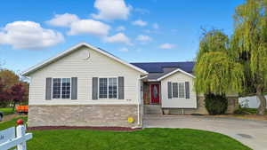 Ranch-style home with roof mounted solar panels and brick siding
