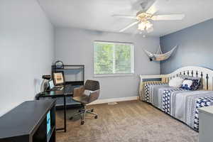 Carpeted bedroom with ceiling fan and a desk