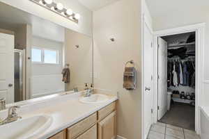 Bathroom with a shower stall, tile patterned flooring, double vanity, and a spacious closet