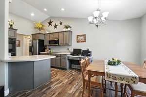 Kitchen featuring appliances with stainless steel finishes, gray cabinets, dark wood-type flooring, light countertops, and a chandelier