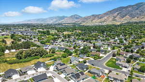 Aerial view of property and surrounding area with mountains and nearby suburban area