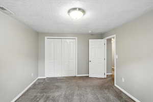 Unfurnished bedroom with carpet flooring, a closet, and a textured ceiling