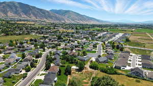Aerial view of property and surrounding area featuring a mountainous background and nearby suburban area