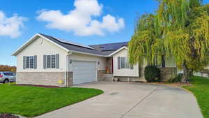 Single story home with a front lawn, driveway, brick siding, a garage, and solar panels