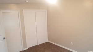 Unfurnished bedroom featuring dark colored carpet and a closet