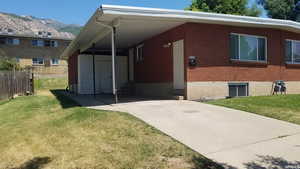 View of front of property with a mountain view, concrete driveway, and a carport