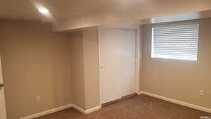 Below grade area featuring dark carpet and baseboards