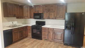 Kitchen featuring black appliances, light wood-style floors, and light countertops