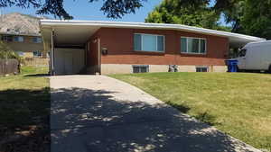 View of front of house with concrete driveway, an attached carport, a mountain view, and brick siding