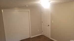 Hall featuring dark carpet and a textured ceiling
