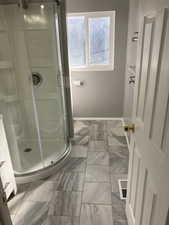 Full bath featuring a stall shower and marble look tile flooring
