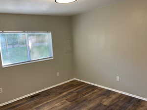 Spare room featuring dark wood finished floors and baseboards