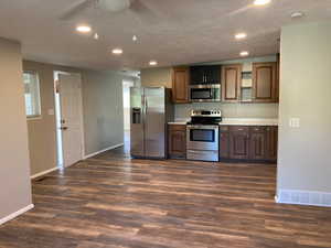 Kitchen featuring appliances with stainless steel finishes, light countertops, recessed lighting, dark wood-type flooring, and a textured ceiling