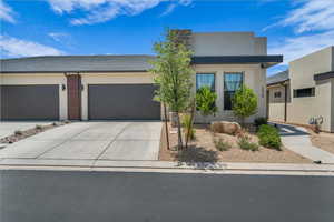 View of front of house featuring concrete driveway, an attached garage, and stucco siding