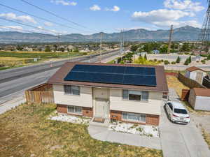 View of front of home featuring a mountain view, solar panels, and brick siding