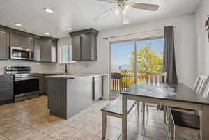 Kitchen featuring stainless steel appliances, backsplash, light stone countertops, ceiling fan, and recessed lighting