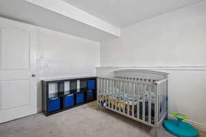 Bedroom featuring carpet and a crib