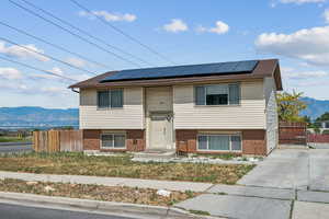 View of front of home featuring a mountain view, roof mounted solar panels, and brick siding