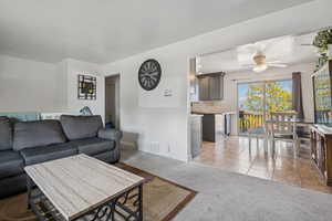 Living area featuring light colored carpet, a ceiling fan, and light tile patterned floors