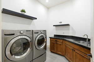 Laundry room with separate washer and dryer, light tile patterned flooring, and cabinet space