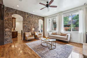 Living area with arched walkways, a ceiling fan, light wood-style floors, and recessed lighting