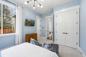 Carpeted bedroom with a chandelier and a closet