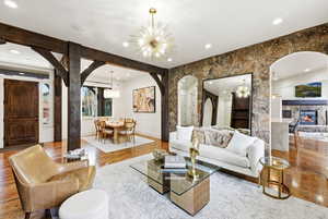 Living room featuring a chandelier, recessed lighting, wood finished floors, arched walkways, and a fireplace