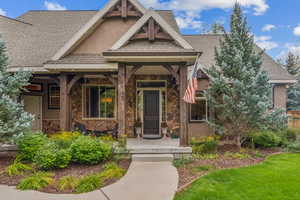 Doorway to property with a shingled roof, a porch, and stone siding