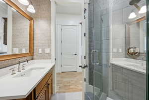 Bathroom with vanity, tile walls, a stall shower, decorative backsplash, and light tile patterned flooring