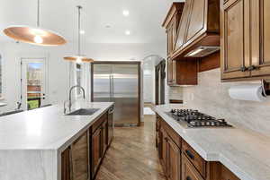 Kitchen featuring decorative light fixtures, light wood-style flooring, stainless steel appliances, light stone counters, and recessed lighting