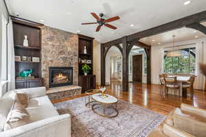 Living area featuring arched walkways, a ceiling fan, wood finished floors, recessed lighting, and a fireplace