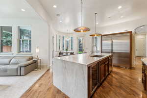 Kitchen featuring stainless steel appliances, light wood-style floors, beverage cooler, open floor plan, and recessed lighting
