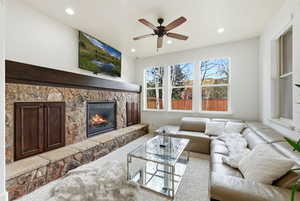 Living area featuring carpet floors, a stone fireplace, ceiling fan, and recessed lighting