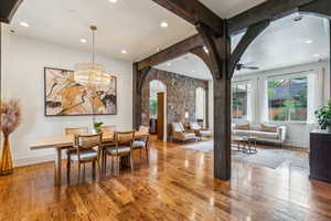 Dining area with arched walkways, wood finished floors, ceiling fan, beamed ceiling, and recessed lighting