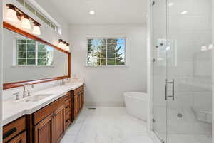 Bathroom featuring a soaking tub, double vanity, a stall shower, light tile patterned flooring, and recessed lighting