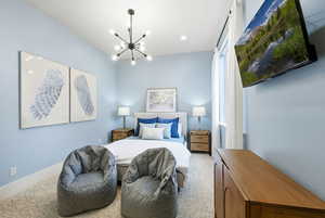 Bedroom with a chandelier, light carpet, and recessed lighting