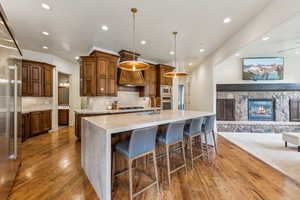 Kitchen featuring a large island with sink, built in appliances, wood finished floors, open floor plan, and recessed lighting