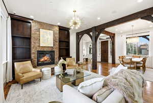 Living room featuring built in features, a chandelier, arched walkways, wood finished floors, and recessed lighting