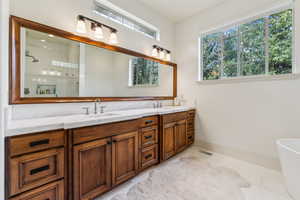 Bathroom with double vanity, tiled shower, plenty of natural light, and a soaking tub